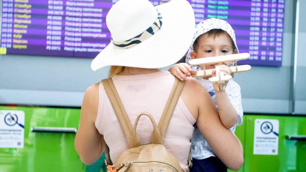Woman at airport carrying child with a backpack style diaper bag