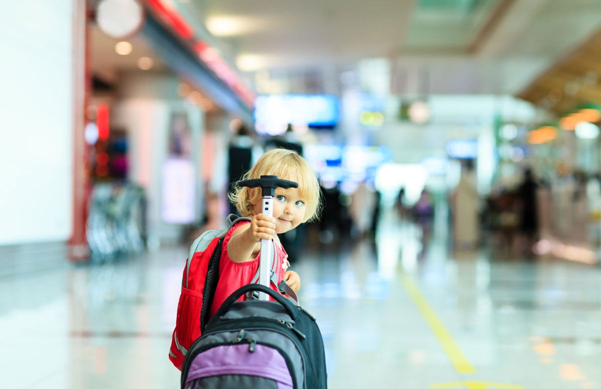 toddler in airport holding handle of suitcase for toddlers