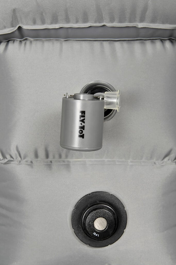 The Fly Tot Tiny Pump lies on top of a Fly Tot Plus airplane cushion to demonstrate how small it is.