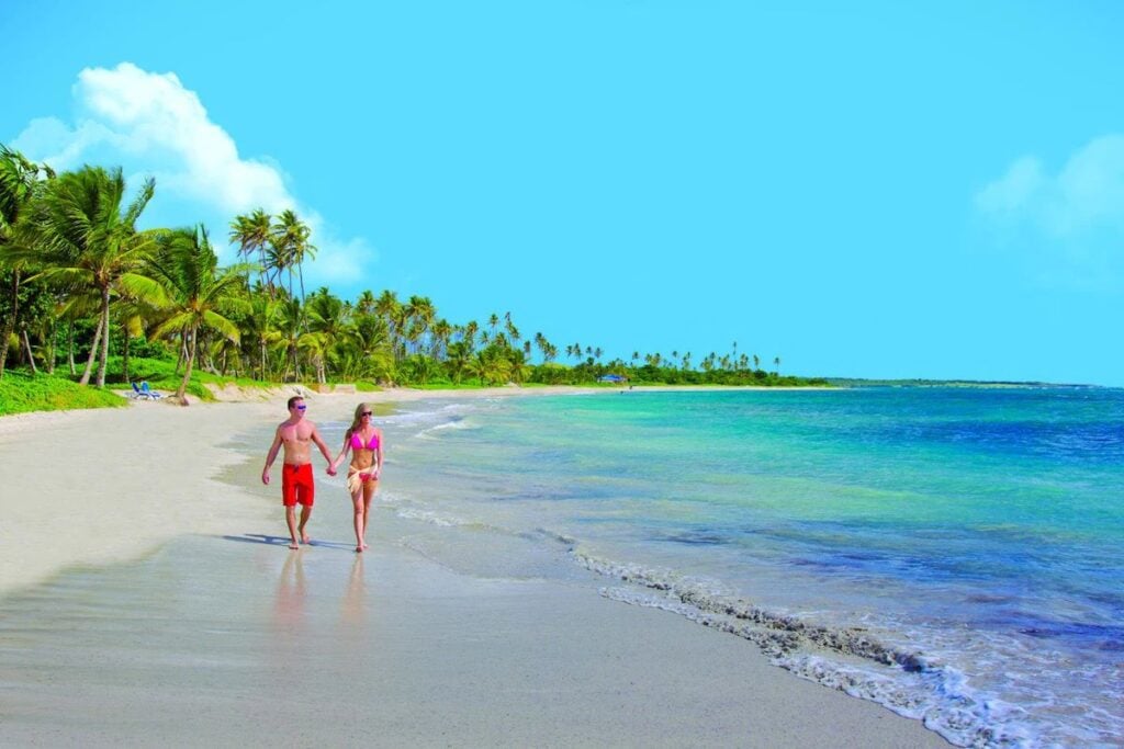 Two adults enjoy a walk on the beach at Coconut Bay Beach Resort & Spa in St. Lucia.